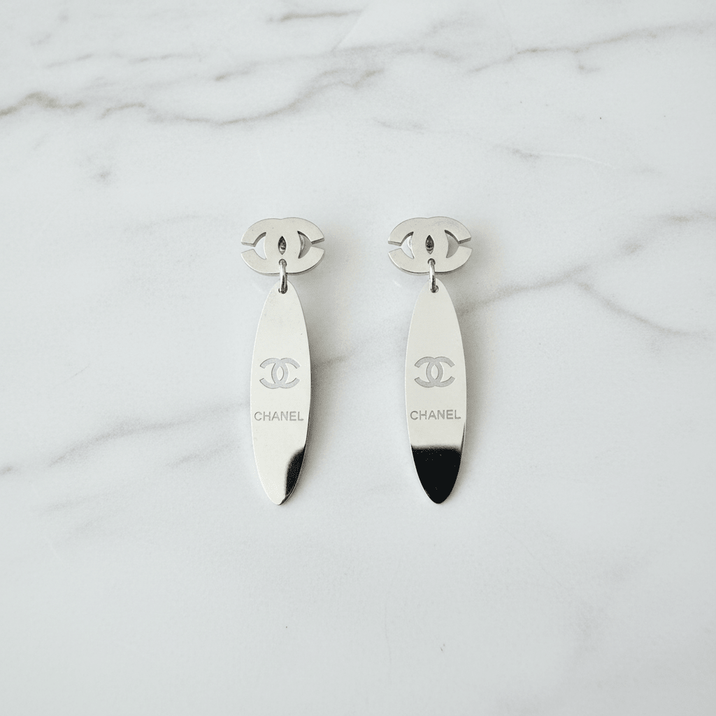 Silver CC logo oval mirror drop earrings on white marble