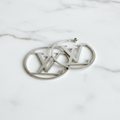 Silver LV logo cutout hoop earrings on white marble surface