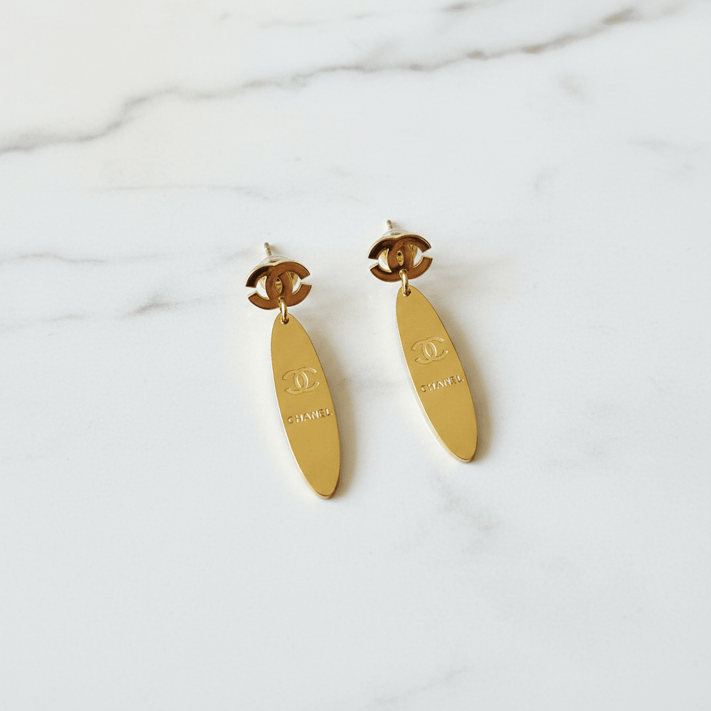 Gold CC logo oval mirror drop earrings on white marble