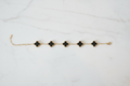 Gold black clover charm bracelet on white marble surface