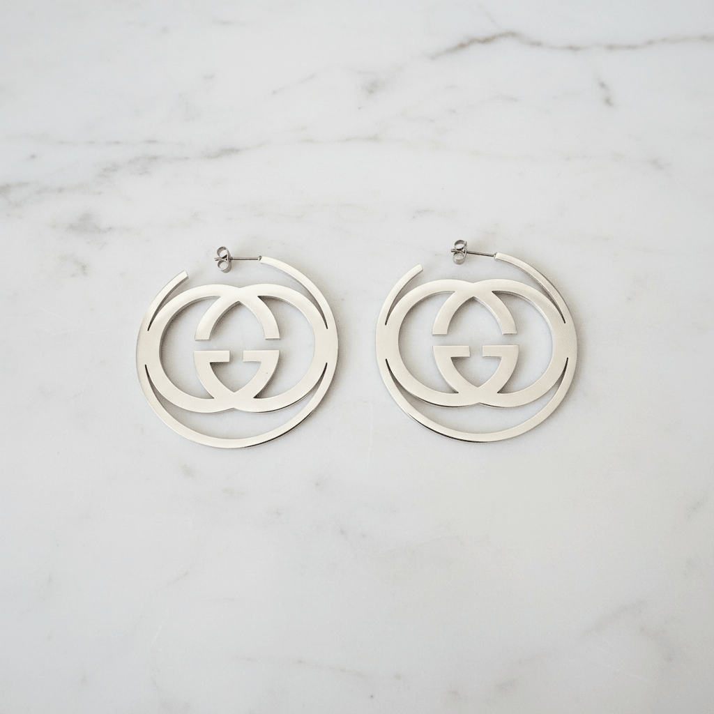 Silver GG swirl hoop earrings on white marble surface