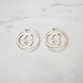 Silver GG swirl hoop earrings on white marble surface